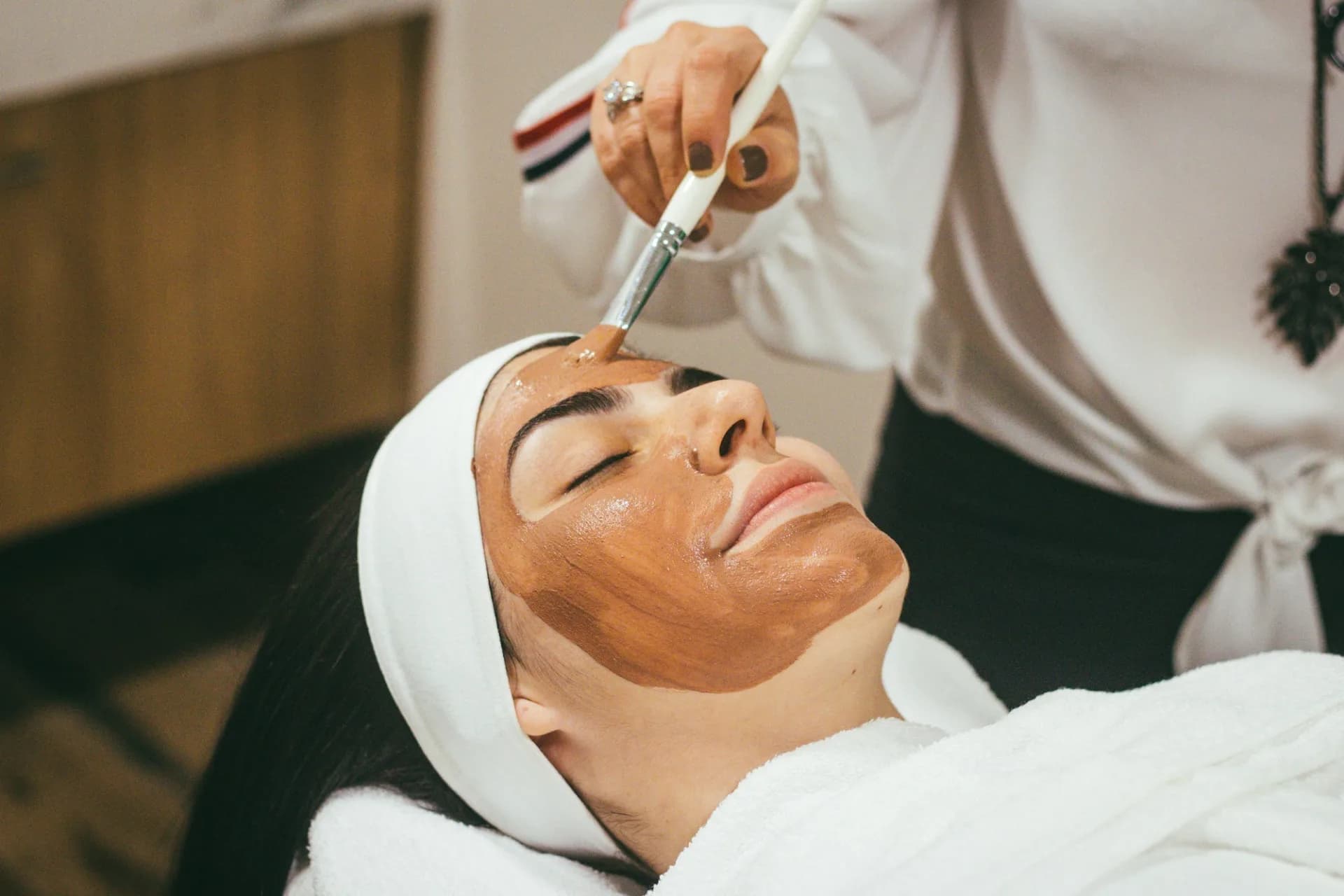 A woman receiving a facial mask treatment at a spa