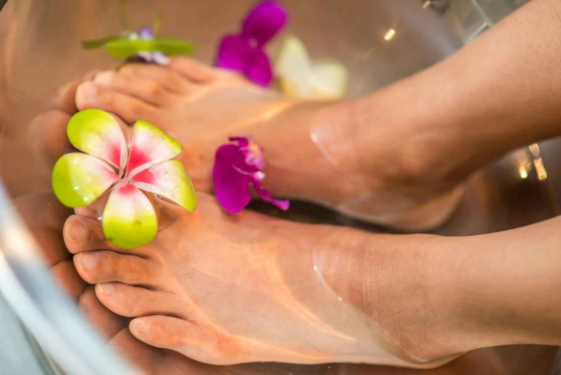 Feet with painted toenails resting beside fresh flowers