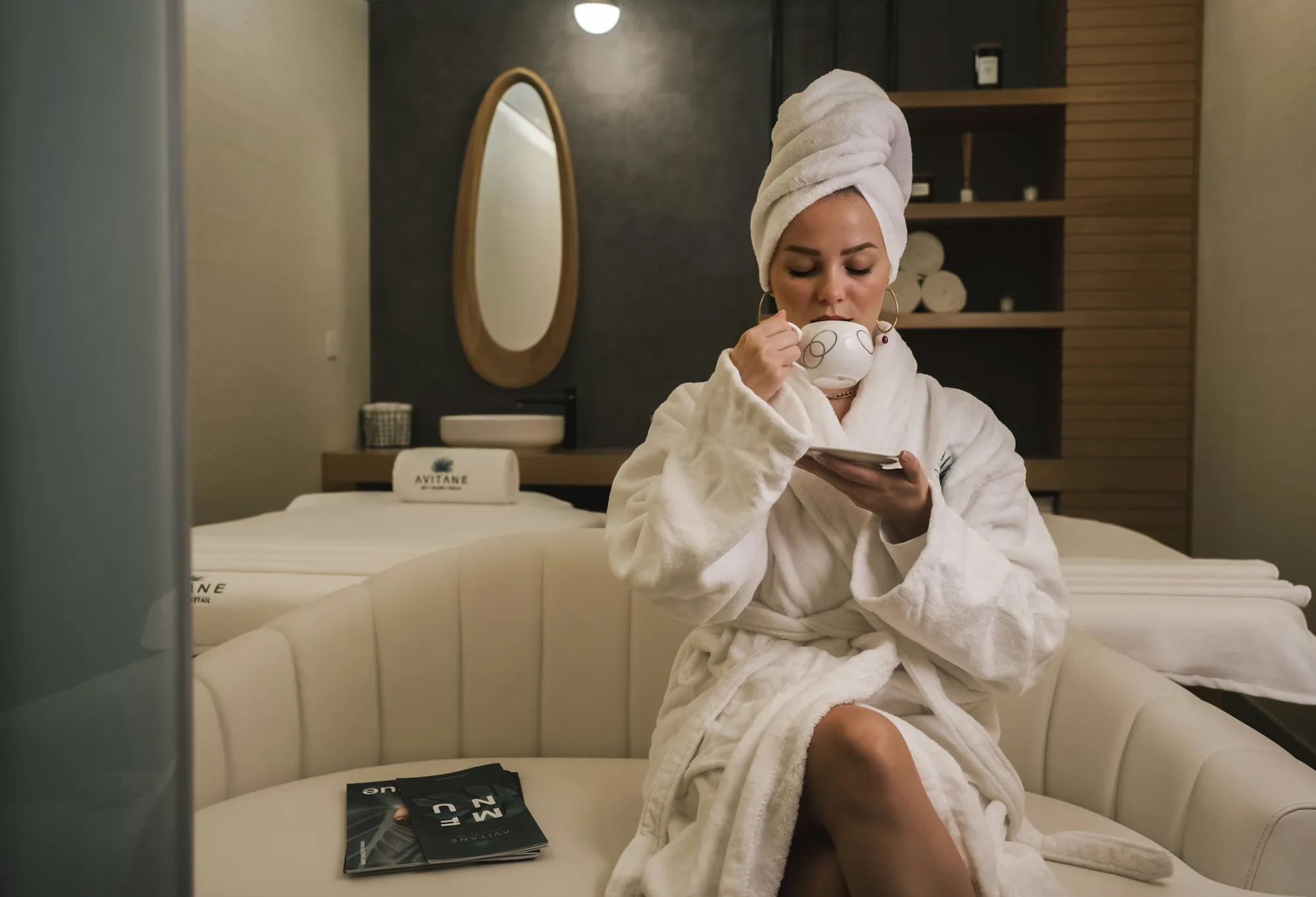 A guest in a white robe relaxing with a cup of tea