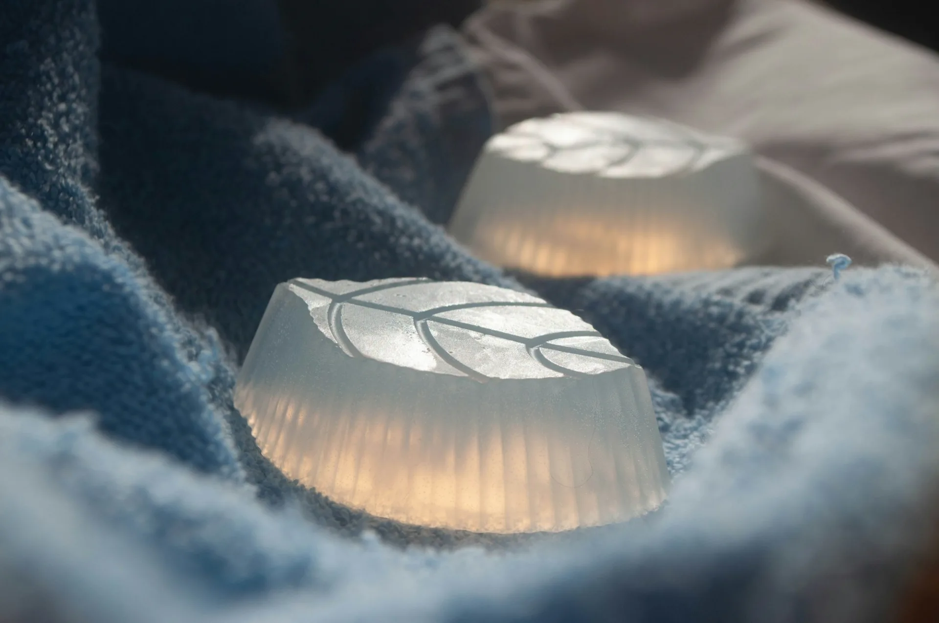 Two translucent soaps with leaf imprints on folded towels