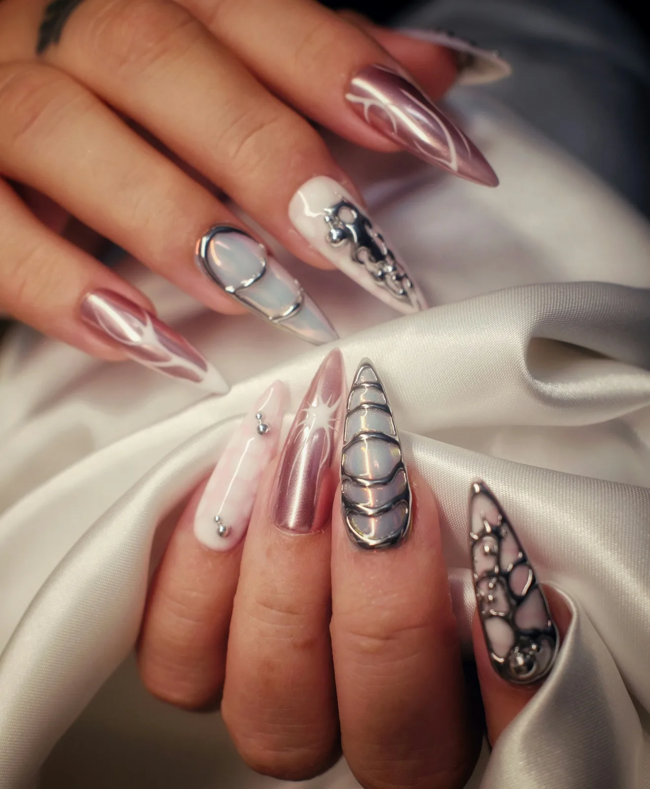 Hands showing long metallic and jeweled nail extensions